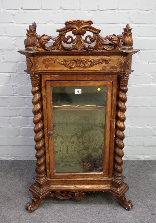 An early 20th century Italian carved giltwood table top display cabinet, with single glazed door and barleytwist mounts on scroll feet, 61cm wide x 10