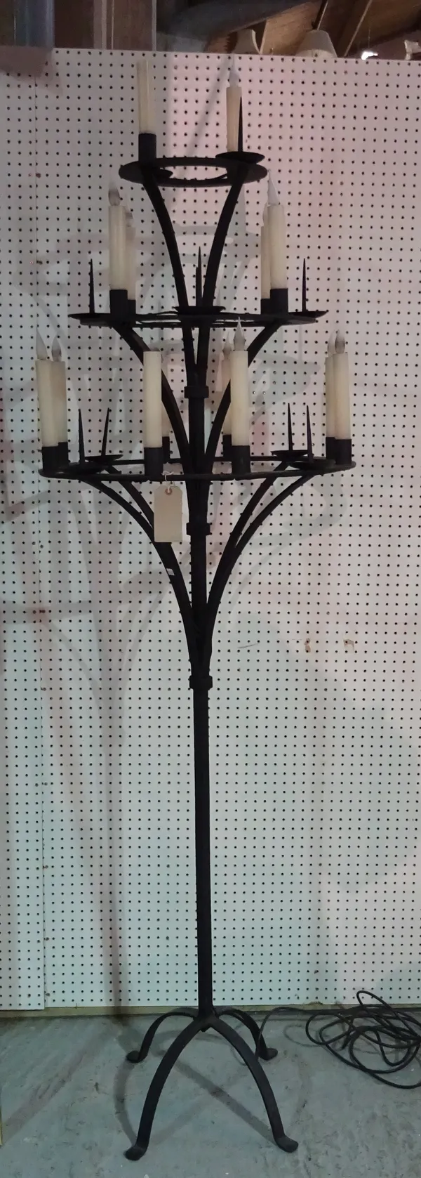 A Medieval style wrought iron candelabra, modern, the three graduated circlets with altar sconces and electric light fitments over a square tubular su
