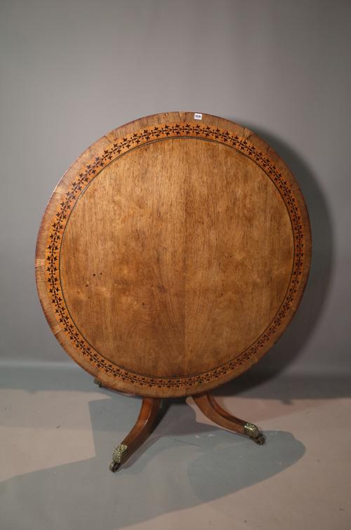 A Regency brass and ebony inlaid circular snap top centre table, on four downswept supports, 130cm wide diameter x 72cm high. Illustrated