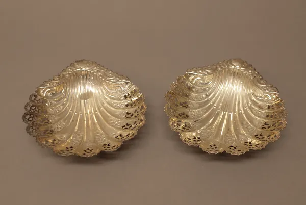 A Victorian pair of silver dishes, each of scallop shell form with pierced and embossed decoration, raised on three fluted spherical feet, Sheffield 1