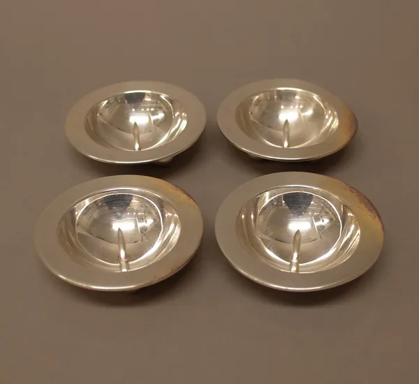 A set of four candle dishes, each of circular form, fitted with a central spike and raised on three hemispherical feet, detailed 925, diameter 9cm, co