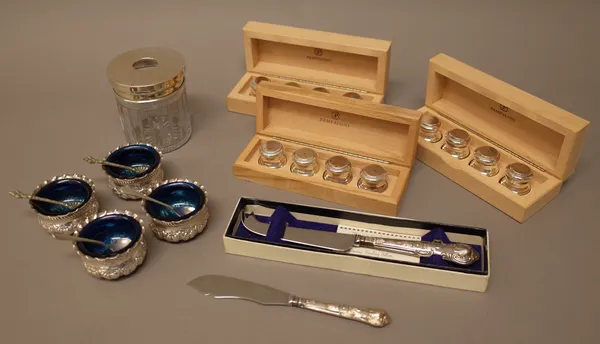 A set of four late Victorian silver circular salts with embossed decoration, London 1897, with blue plastic liners, a silver lidded glass hair tidy ja