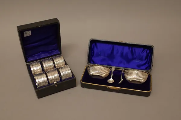 Silver, comprising; a set of six napkin rings, with scroll engraved decoration, Chester 1902, with a case and a pair of boat shaped salts, with fluted