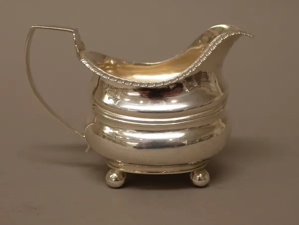 A George III silver milk jug, of helmet shaped form, decorated with a gadrooned rim and raised on four spherical feet, London 1819, weight 104 gms.