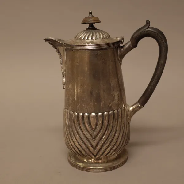 A silver hot water jug, with a partly fluted body and hinged lid, raised on a reeded circular foot and with black composition fittings, Birmingham 190