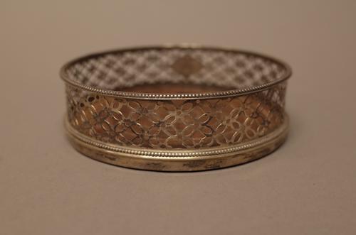 A silver mounted circular bottle coaster, with later pierced decoration within beaded rims and with a turned wooden base, diameter 12cm, London 1615