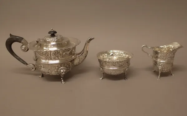 A silver three piece teaset, comprising; a teapot, a sugar bowl and a milk jug, each piece embossed with flowers and animals and raised on three lion