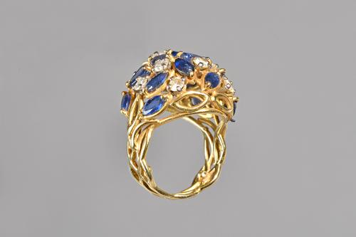 An 18ct gold, sapphire and diamond ring, pierced in an open work abstract foliate design, claw set with marquise shaped sapphires and with circular cu