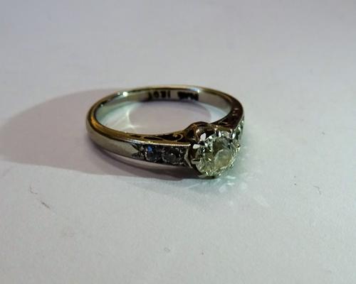 A platinum and white gold, diamond ring, claw set with the principal cushion shaped diamond between diamond two stone shoulders, detailed PLAT 18CT, r