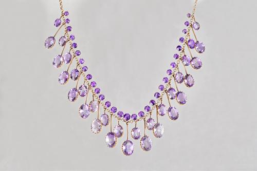 A gold and amethyst necklace, the front mounted with a row of circular cut amethysts above a two tier row of graduated oval cut amethyst set pendant d