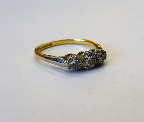 A gold and platinum, diamond set three stone ring, claw set with the principal circular cut diamond at the centre, between two smaller circular cut di