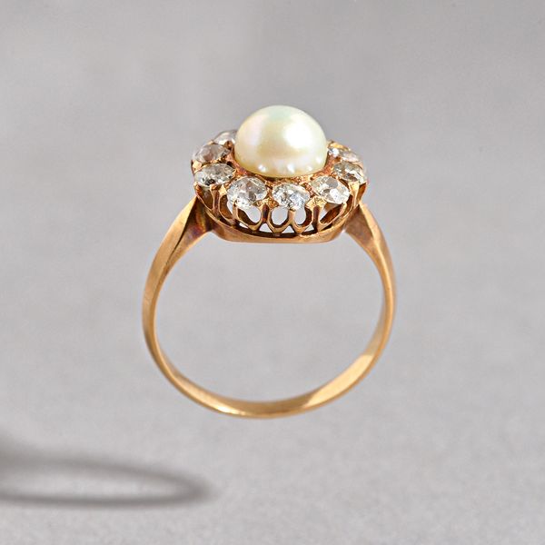 A gold, diamond and cultured pearl cluster ring, mounted with a single cultured pearl in a surround of ten cushion shaped diamonds, ring size K and a