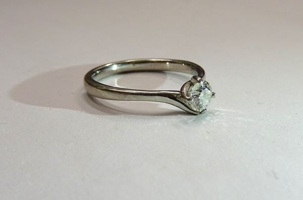 A platinum and diamond single stone ring, claw set with a circular cut diamond in a twistover design, ring size K.