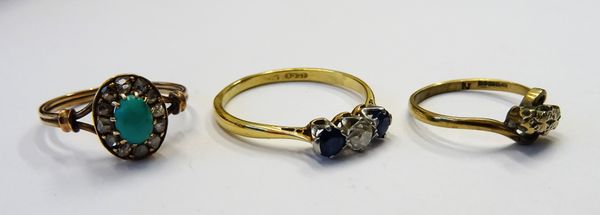 A gold and platinum, sapphire and diamond set three stone ring, claw set with a cushion shaped diamond at the centre, between two cushion shaped sapph