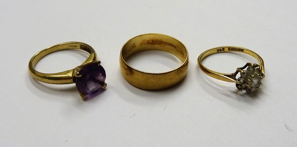 A 9ct gold ring, claw set with a circular cut amethyst, a 9ct gold and colourless gem set cluster ring and a 9ct gold plain wedding ring, gross combin