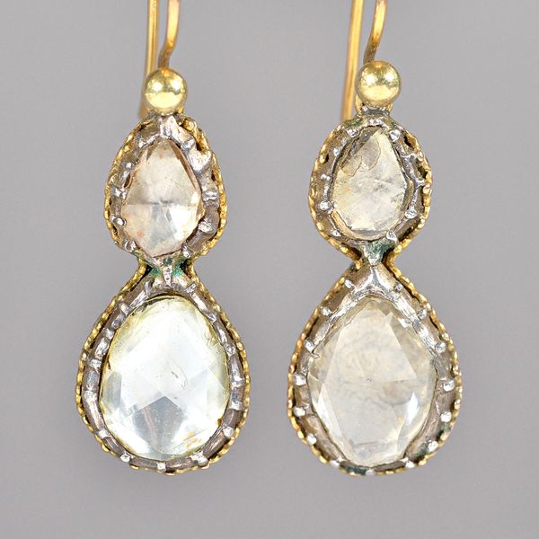 A pair of gold and silver set, diamond two stone pendant earrings, each mounted with the principal foil backed rose cut diamond below a smaller foil b