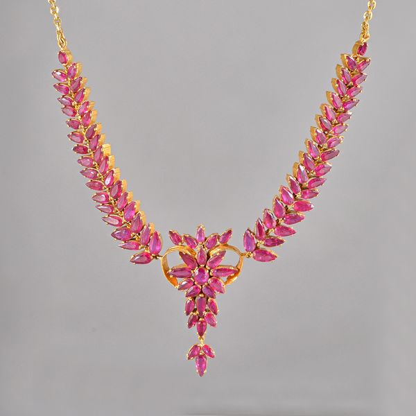 A gold and ruby necklace, the front with a central foliate cluster, between tapered foliate sides, mounted with pear shaped rubies, on an oval snap cl