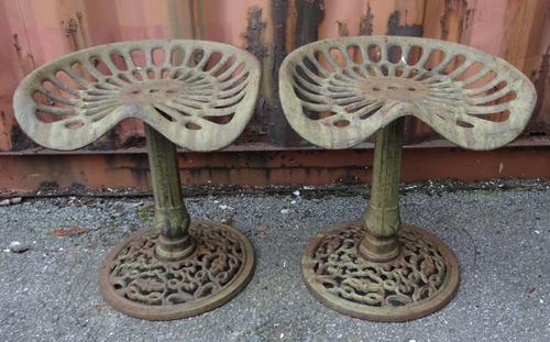 A pair of early 20th century cast iron stools previously tractor seats, 45cm wide x 49cm high (2).  OUT