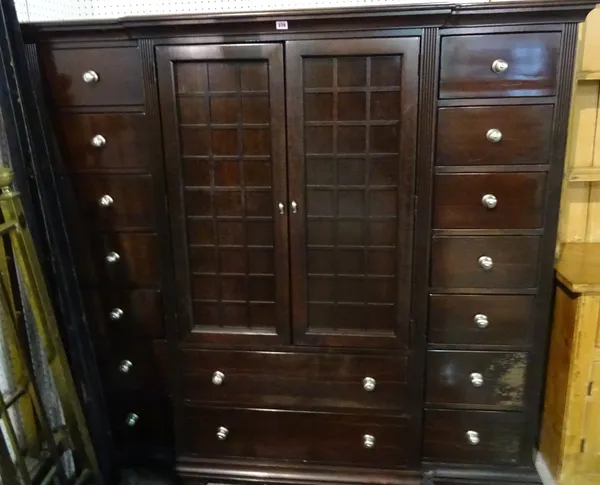 A 20th century hardwood side cabinet with a pair of cupboard doors over three long drawers flanked by seven short drawers on plinth base, 170cm wide x