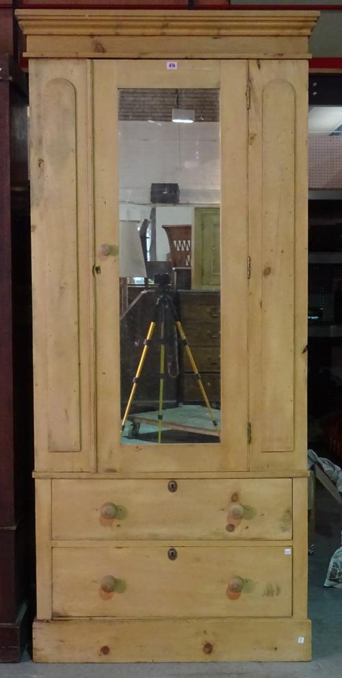 A 20th century pine wardrobe with mirrored door over two drawers on plinth base, 94cm wide x 203cm high.   M9