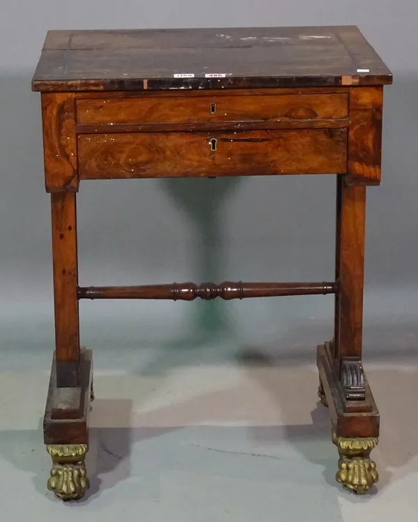 A William IV rosewood work table, with rectangular lift top over single drawer, on trestle end standards and four carved and gilded lion's paw feet (a