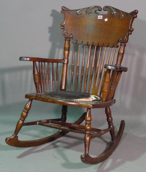 A late 19th century oak American rocking open armchair, with spindle back and turned supports.  I10