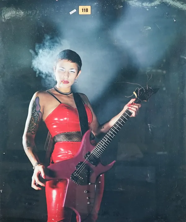UNKNOWN:  (Contemporary)  Girl wearing red leather jumpsuit, playing a guitar, ca. 1977. polaroid large format colour instant print, 60cm x 51cm, fram