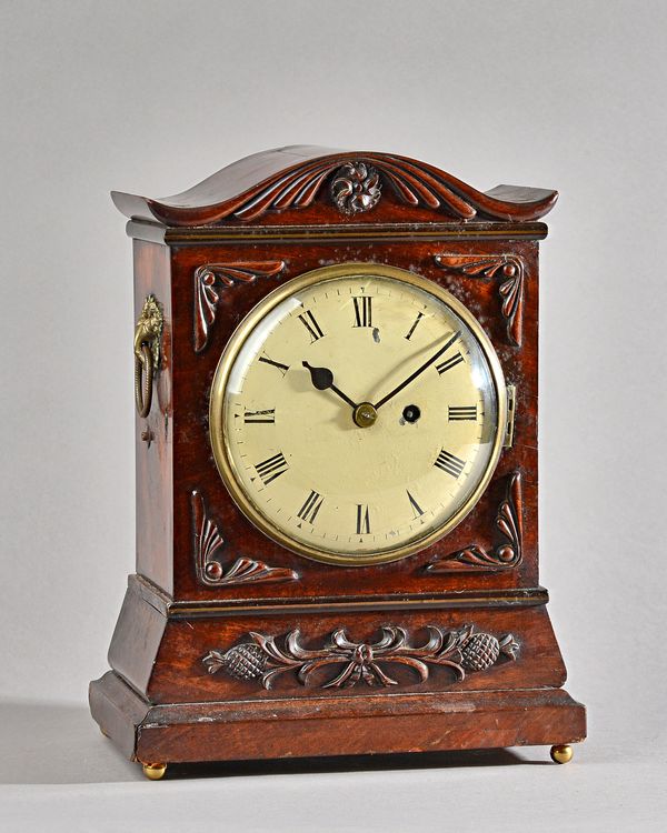 A Victorian mahogany cased mantel clock with shaped top and carved foliate embellishments, with painted tin dial and single train movement, 34cm high.