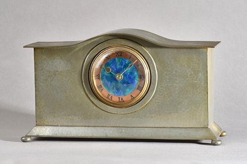 A Liberty & Co mantel clock, No.01126, hammered pewter case with enamel dial, stamped marks to base, 17.7cm high x 32cm wide.  Illustrated