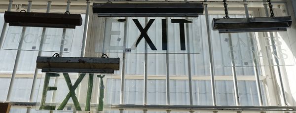 Four mid-20th century illuminated glass and chrome signs comprising; two 'Exit', a 'Ladies Cloaks' and 'tickets', the largest 57cm wide (4).