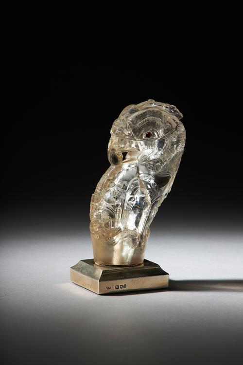 A 19th century Continental carved rock crystal parrot, probably a parasol handle, red hardstone eyes (garnets?), now set on a rectangular base with si
