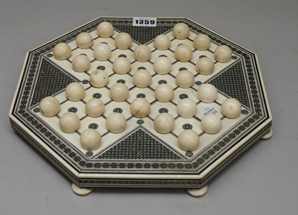 An early 20th century Indian ivory solitaire board of octagonal form, with intricate Sadeli style foliate geometric inlay, on eight bun feet, 28cm wid