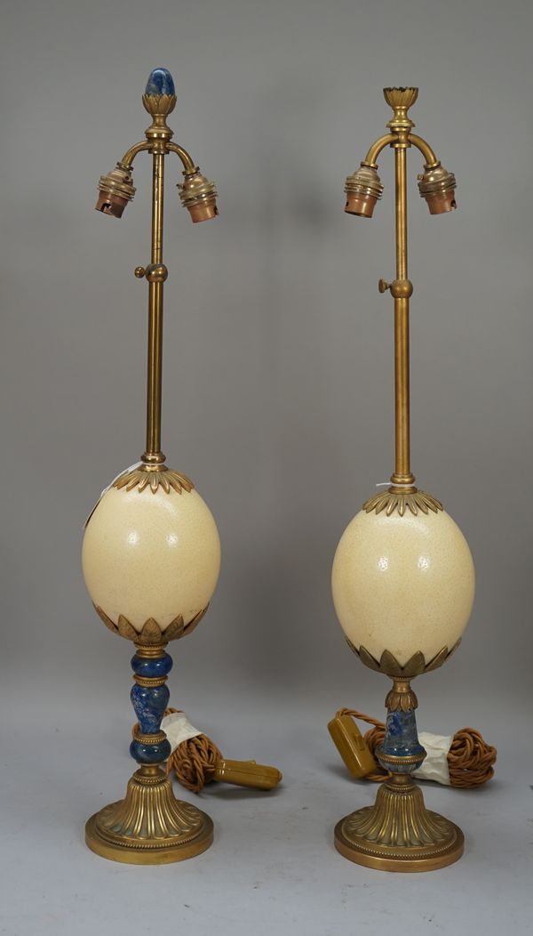 A near pair of brass and Lapis mounted table lamps with ostrich egg mount to the stem over a fluted circular foot with cream pleated shades, 70cm high