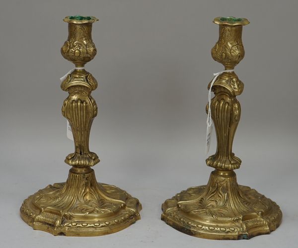 A pair of French gilt patinated brass candlesticks, late 19th century, each foliate cast on a spreading foot, 23.5cm high, (2).