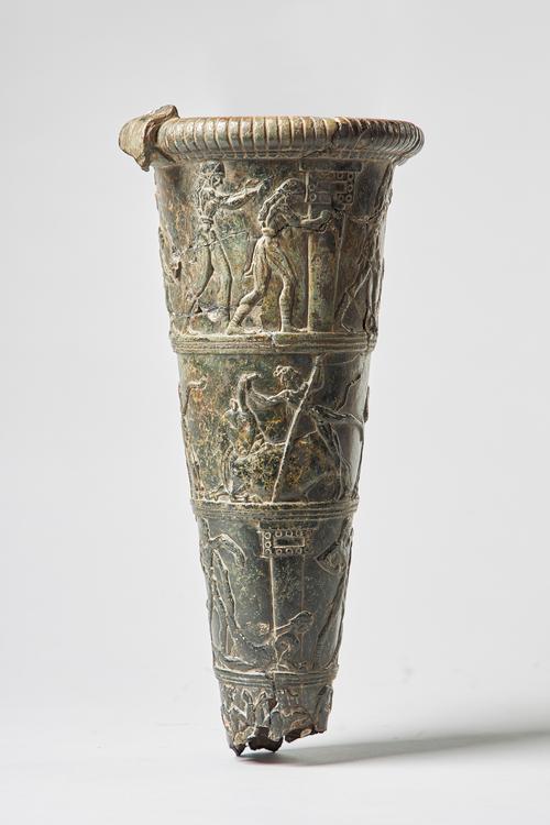 A Minoan style Rhyton in black steatite, carved with bands of boxing and bull fighting against a tapering cylindrical body, 30cm, (a.f.).