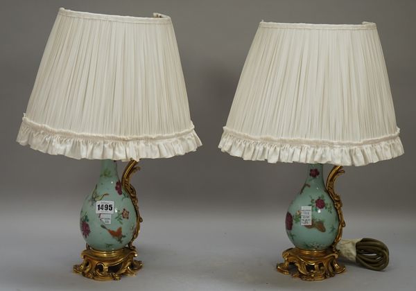 A pair of Chinese porcelain and ormolu mounted ewer table lamps, with pleated cream shades, 44cm high, (2).