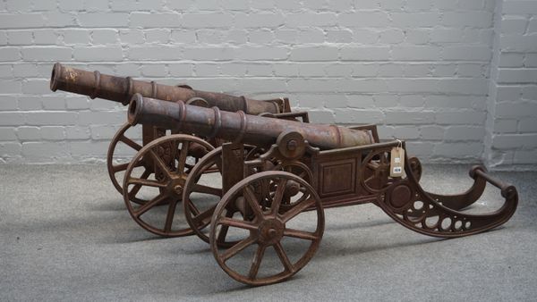 A pair of reproduction cast iron cannons, late 20th century, with circular tapering barrels, pierced frames and spoked wheels, 160cm wide, (2).