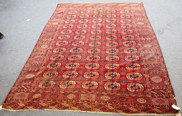 A Tekke Turkeman carpet, the madder field with five columns of twelve guls, supporting cross motifs, a bold sunburst border, 288cm x 216cm.