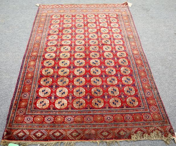 A part silk Tekke Turkman rug, the madder field with five columns of thirteen guls, supported by cross motifs; a sunburst border, 223cm x 142cm.