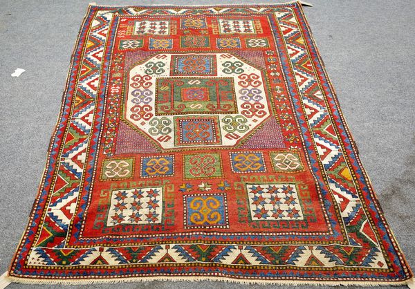 A Karachov rug, Caucasian, the madder field with a bold ivory medallion, squared motifs at each end, a leaf and stylised tulip border, 223cm x 160cm.