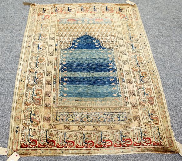 A Ghirodes prayer rug, Turkish, the plain banded indigo mehrab rising to a leaf filled arch; a plant border, 176cm x 121cm.