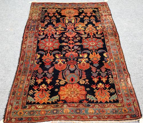 A Bakhtiari rug, Persian, the dark indigo field with bold flowerheads and stylised plants; an indigo flowerhead border, 194cm x 120cm.