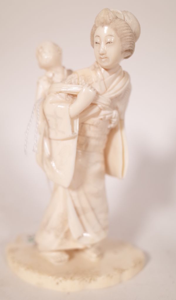 A Japanese ivory okimono of a bijin, Meiji period, carved walking carrying a young child across her back, signed in a red lacquer reserve, 14.5cm. hig