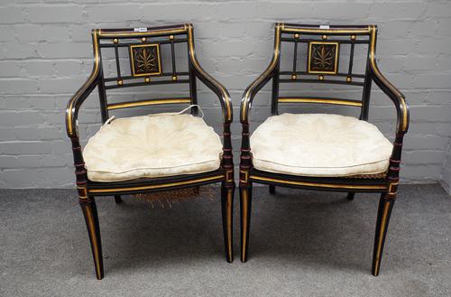 A pair of Regency style parcel gilt ebonised open armchairs on sabre supports, 54cm wide x 80cm high. (2)