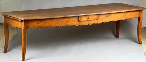 A 19th century French fruitwood kitchen table, the extendable cleated plank top over a single drawer wavy frieze on cabriole supports, 89cm wide x 285