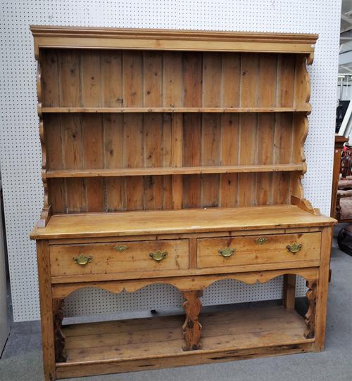 An early 19th century pine dresser, the enclosed two tier plate rack over a pair of frieze drawers on silhouette baluster supports, united by potboard