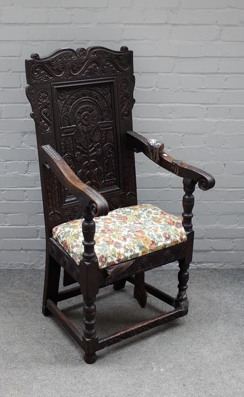 A Charles I carved oak panel back open armchair, on baluster turned supports, 61cm wide x 130cm high.