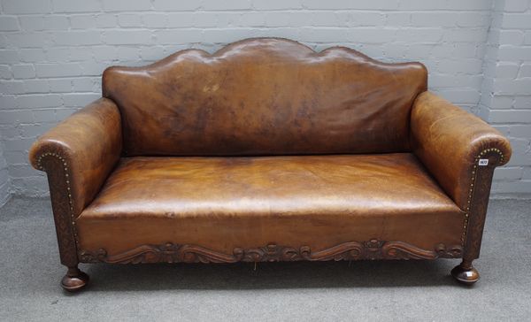 A 20th century brown leather upholstered hump back sofa with carved lower frieze, 165cm wide x 61cm high.