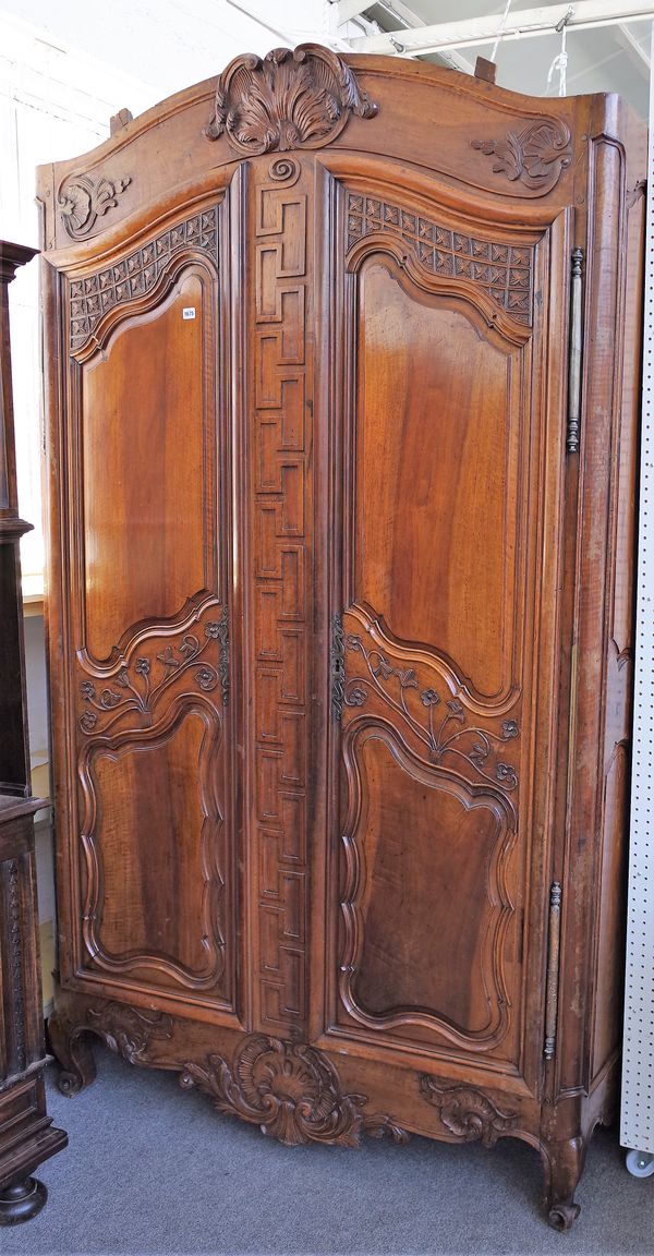 An 18th century fruitwood armoire with carved arched cornice over a pair of shaped panel doors, on scroll feet, 166cm wide x 258cm high.  11