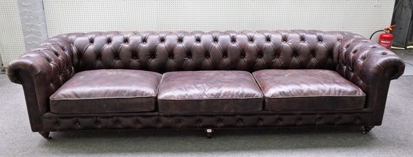 A large brown leather upholstered Chesterfield sofa, on turned supports, 300cm wide x 69cm high.